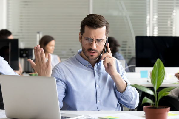 Angry businessman caller talking on phone disputing over computer problem